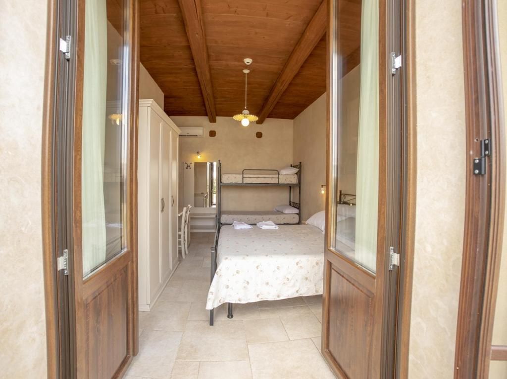 Una camera funzionale con un letto a castello, un letto singolo, un armadio e un angolo cottura.