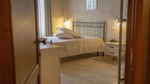 A bedroom with a bed, bedside table, and a small cabinet. - Masseria Chinunno (Altamura)