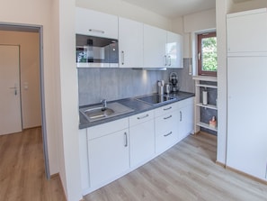 A modern kitchen with white cabinets, a stainless steel sink, and a built-in oven.
