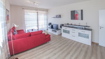 A modern living room with a red sofa, a TV, and a white cabinet.