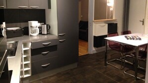 Une cuisine moderne équipée d’un grille-pain encastré, d’une machine à café et d’un coin repas avec une table et des chaises.