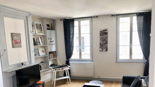 Un salon avec un téléviseur, une bibliothèque, une petite table et un canapé.
