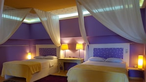 Quarto com duas camas, um banco e duas mesas de cabeceira com luminárias.