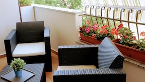 A balcony with wicker furniture, a potted plant, and a striped awning. - Zama Bed&Breakfast (Scalea)