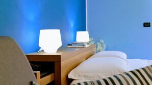 A bedroom with a wooden nightstand, two bedside lamps, a stack of books, and a bed with striped pillows. - Zama Bed&Breakfast (Scalea)