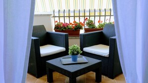 A balcony with wicker furniture, a small table, and potted plants. - Zama Bed&Breakfast (Scalea)
