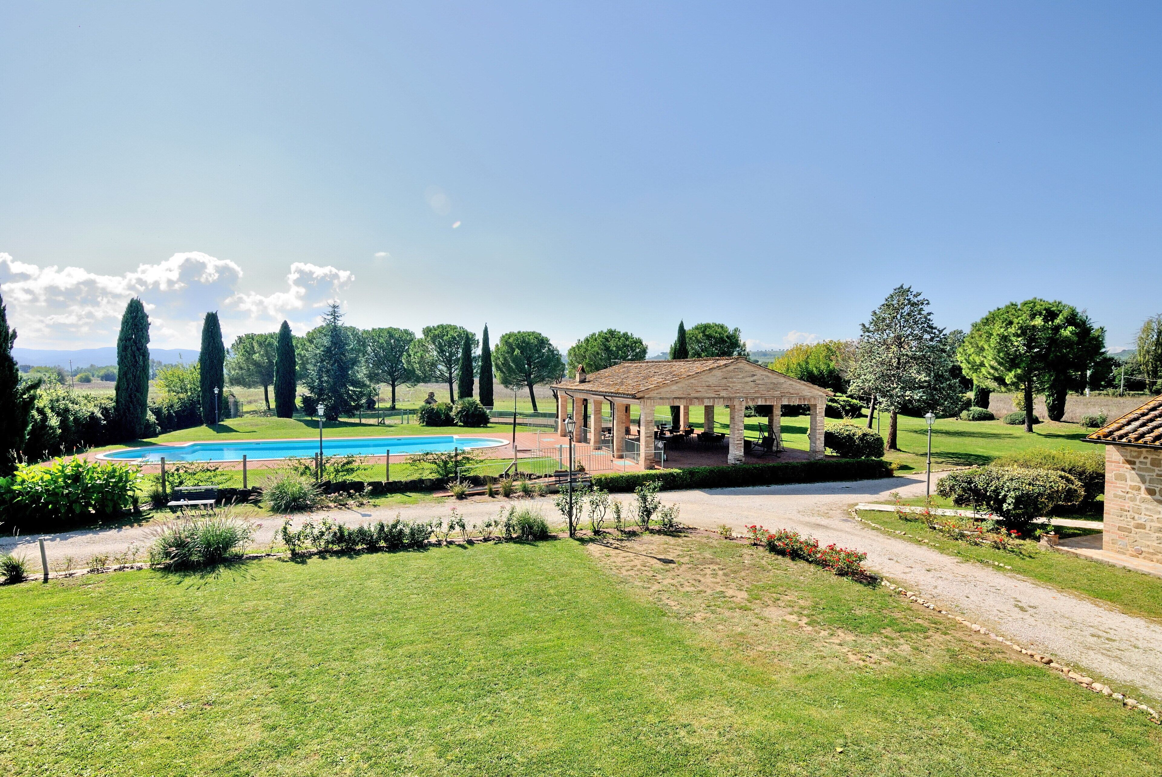 A garden with a gazebo, a swimming pool, and a clear sky.