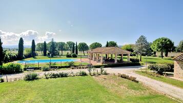 A garden with a gazebo, a swimming pool, and a clear sky.