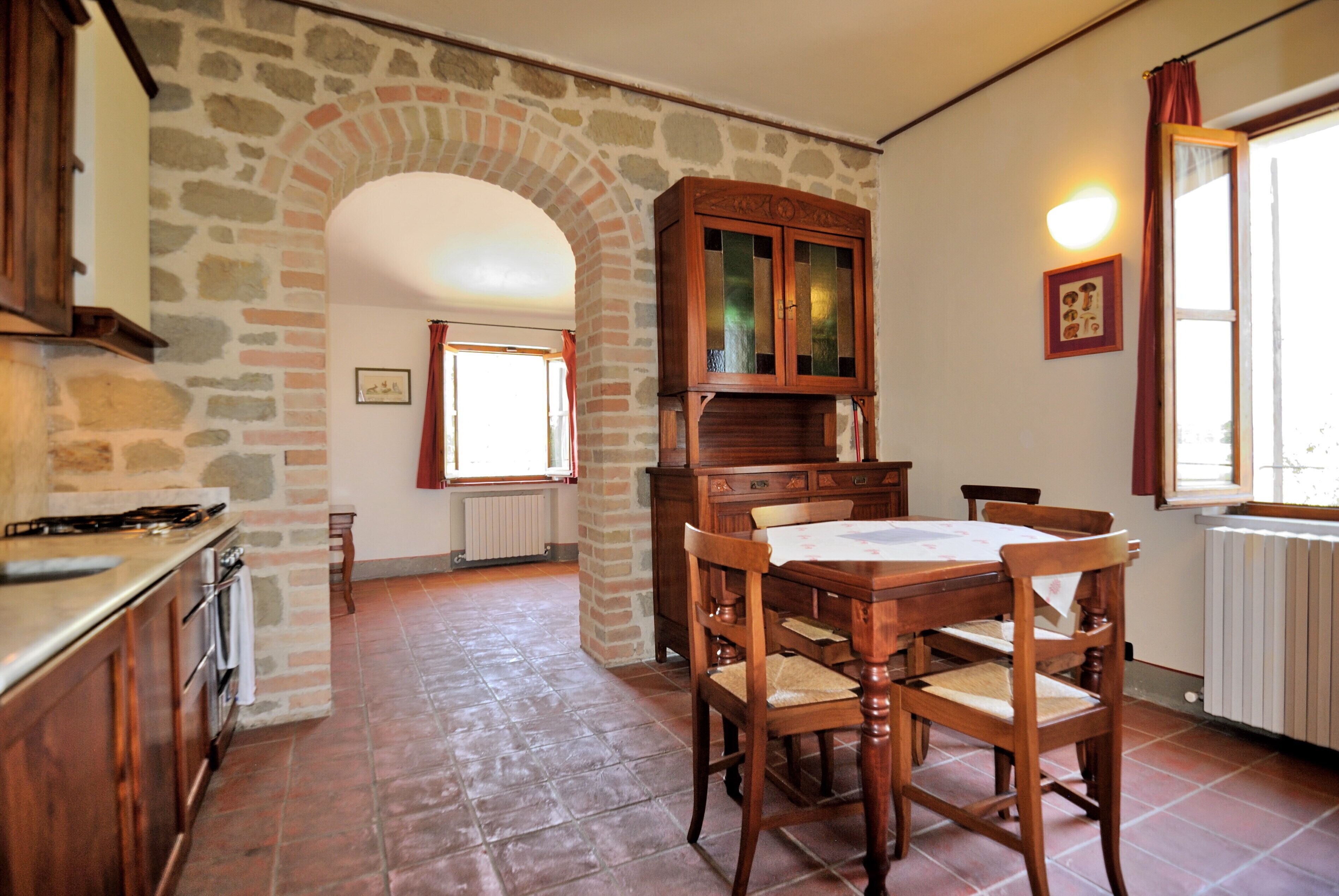 Une cuisine aux murs en pierre, avec une table à manger en bois et des chaises.
