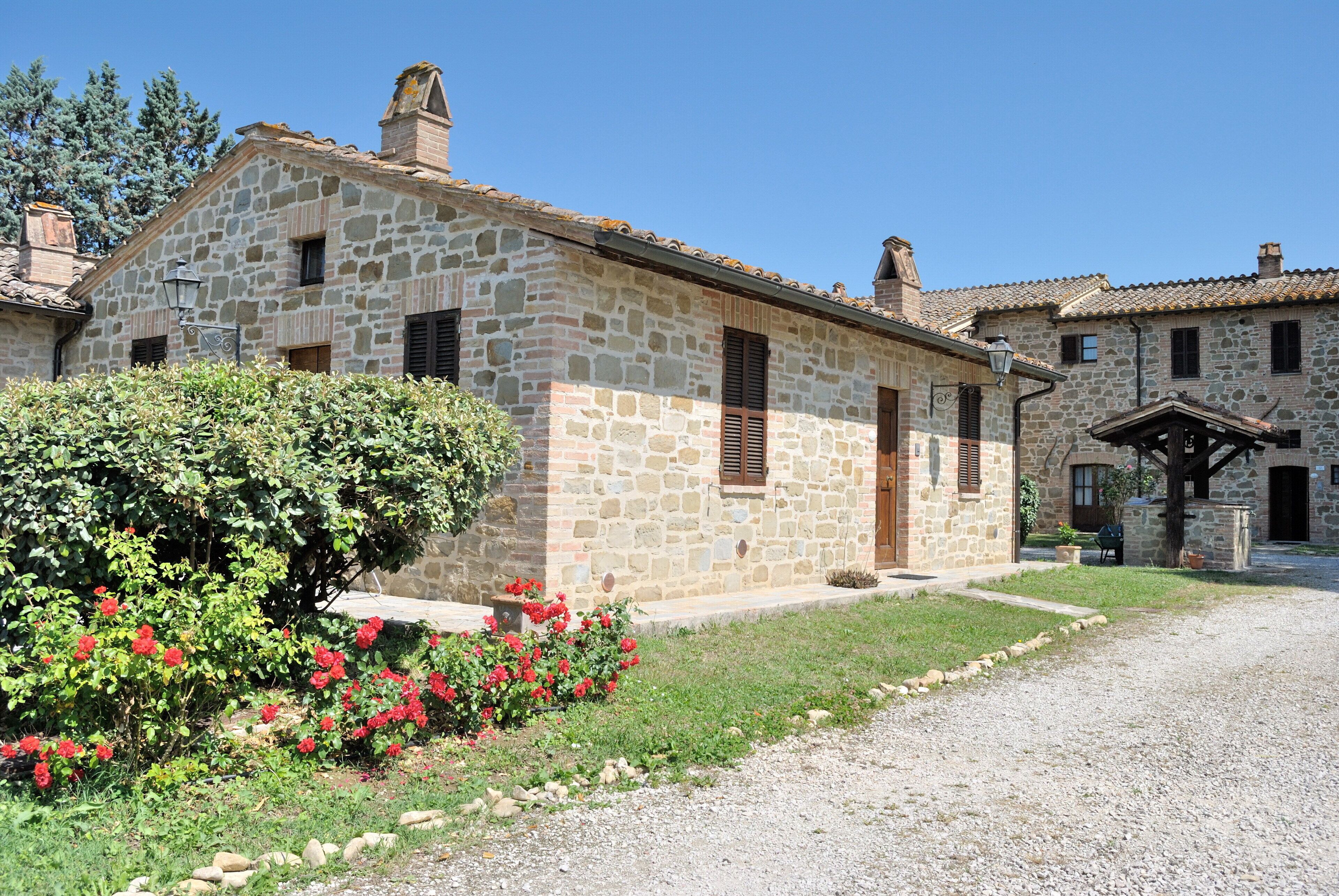 Un bâtiment en pierre avec un jardin devant.