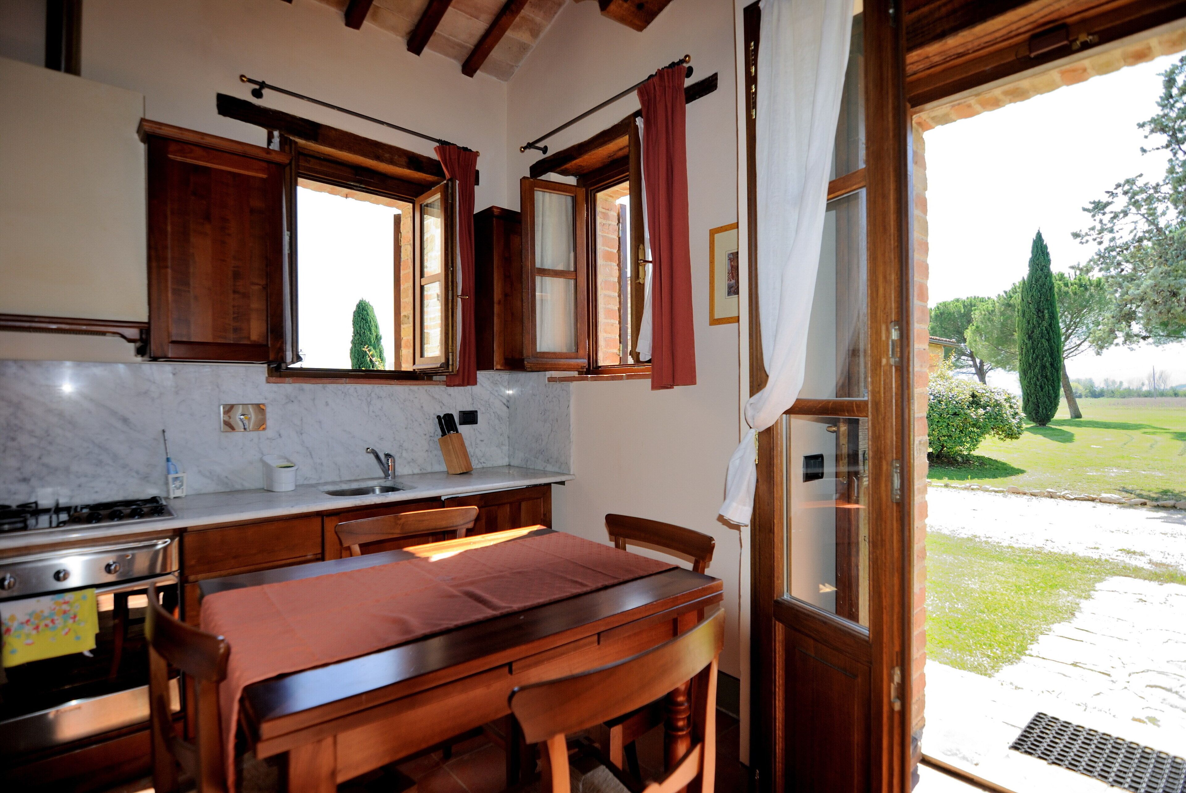 A kitchen with wooden cabinets, a marble countertop, and a dining area with a table and chairs.