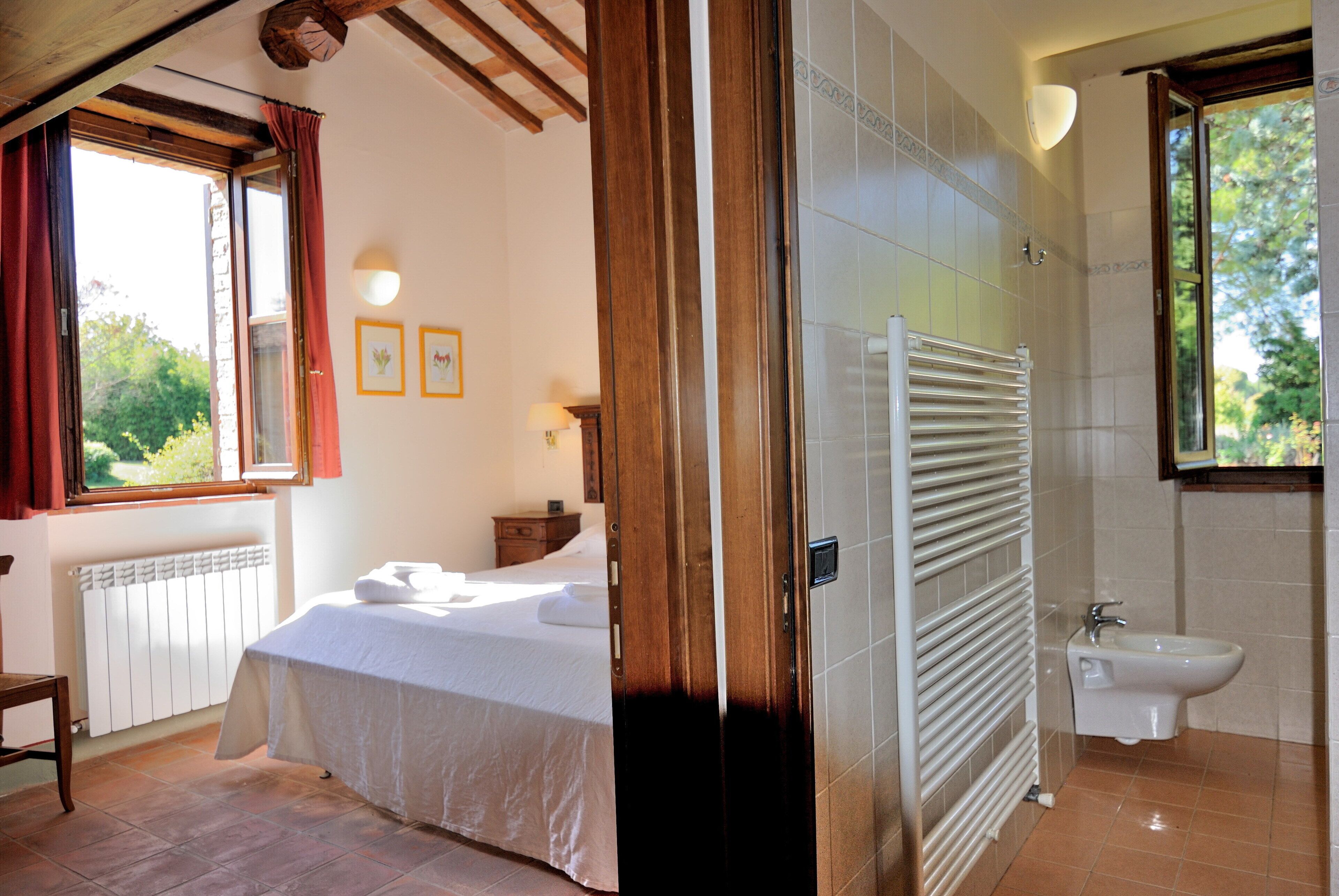 A bedroom with a bed, a bedside table, and a window with curtains.