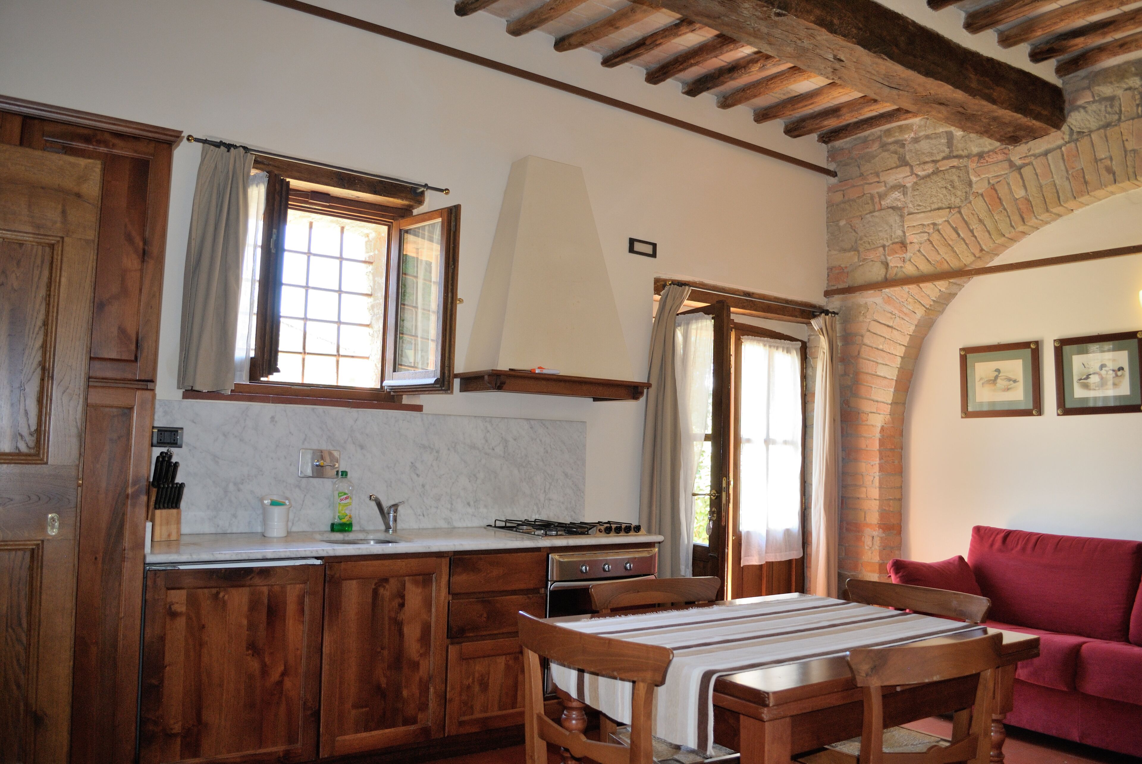 Una cocina con armarios de madera, una estufa y una mesa de comedor con sillas.