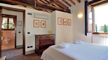 A bedroom with a wooden ceiling, a bed with white linens, a dresser, and framed pictures on the wall.