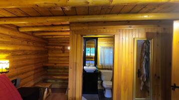 L’intérieur d’une cabane en bois comprend un lit, une petite table, un banc, un évier et des toilettes.