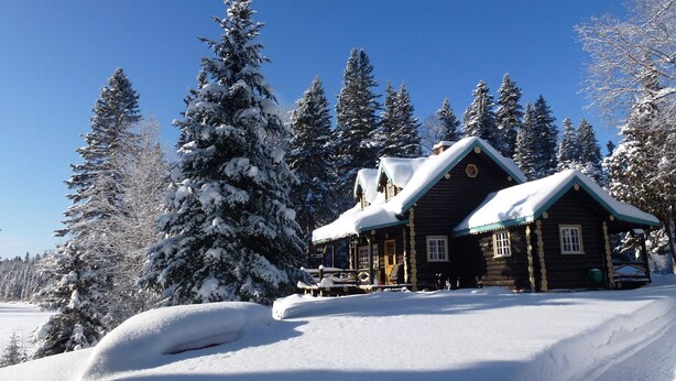 A log cabin with a snow-covered roof and a clear blue sky. - Domaine le Bostonnais (La Bostonnais)
