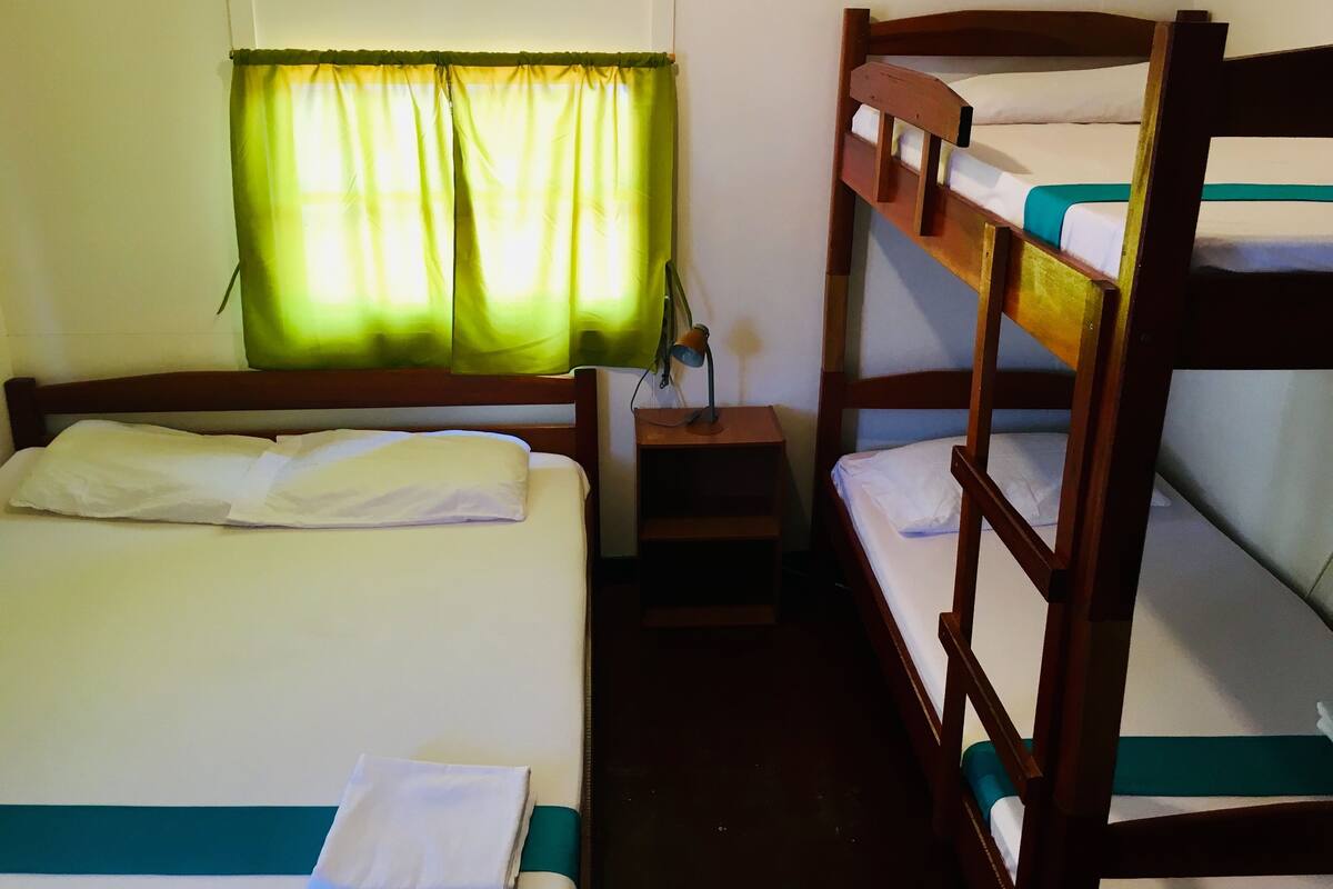 Une chambre avec un lit superposé, une fenêtre et une table de chevet.