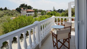 A balcony with a white railing, a small table, and two chairs. - Orestis Suites (Skiathos)