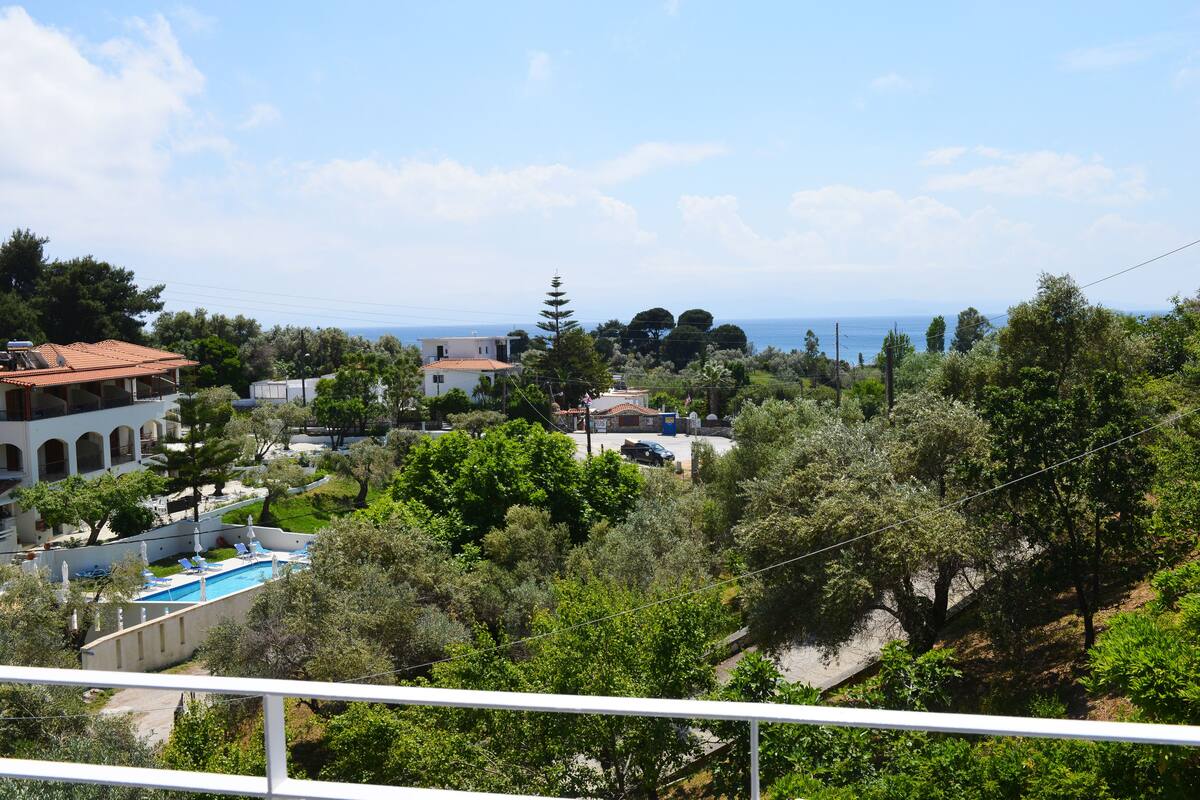 A residential area with a swimming pool, trees, and a view of the sea.