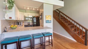 Une cuisine moderne dotée d’un îlot central, de tabourets de bar et d’un escalier menant à un niveau supérieur.