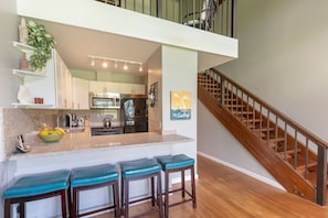 Enjoy cooking in this kitchen with a central island, oven, and sink, plus a staircase leading to an upper level.