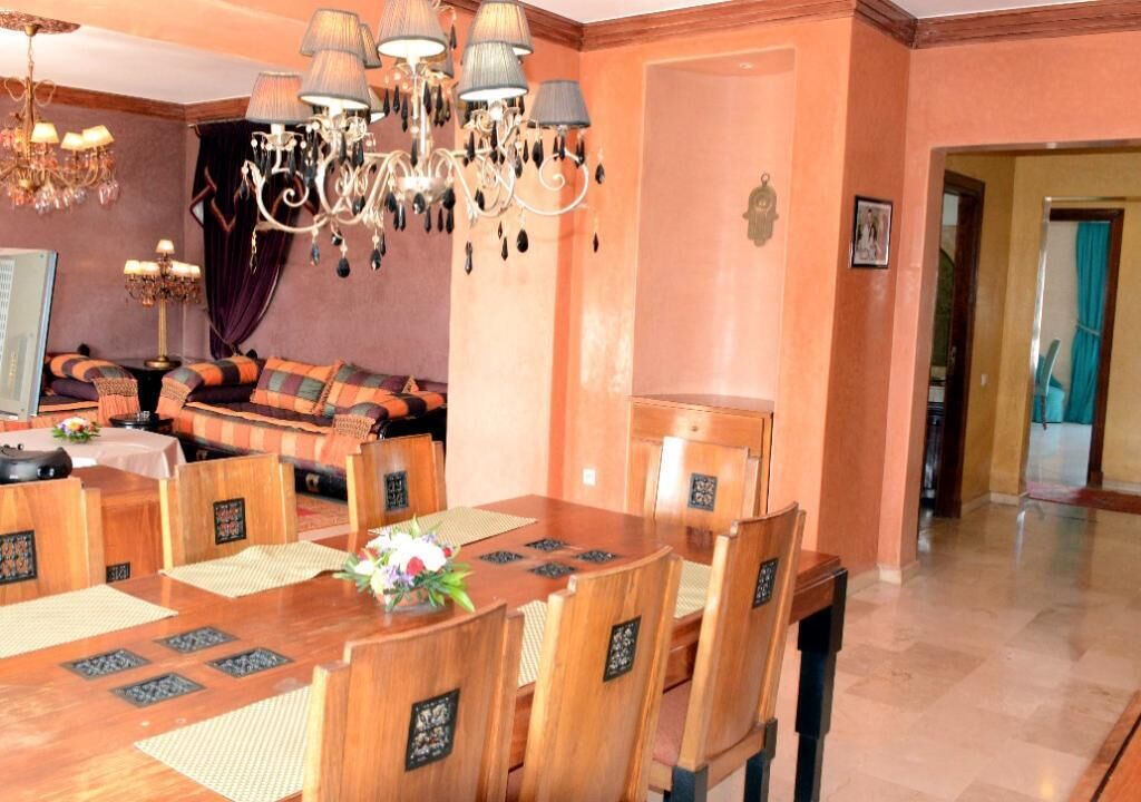 A dining area with a wooden table, chairs, and a chandelier.