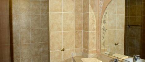A bathroom with beige tiles, a large mirror, a white sink, and a towel on the counter.