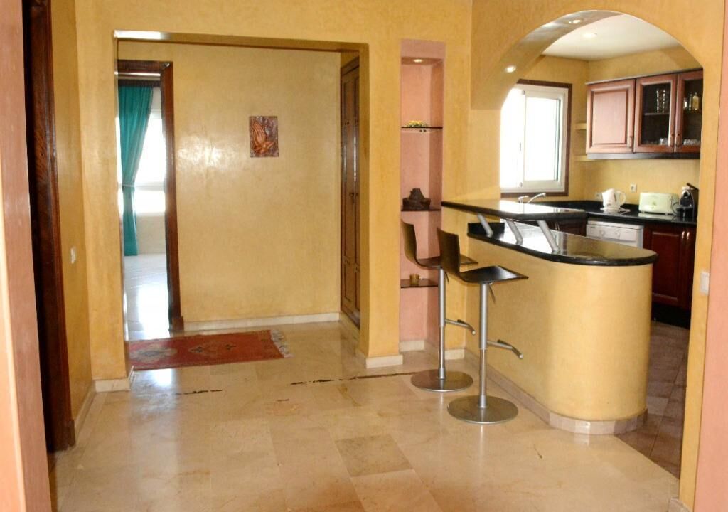 A kitchen with a central island, bar stools, and wooden cabinets.