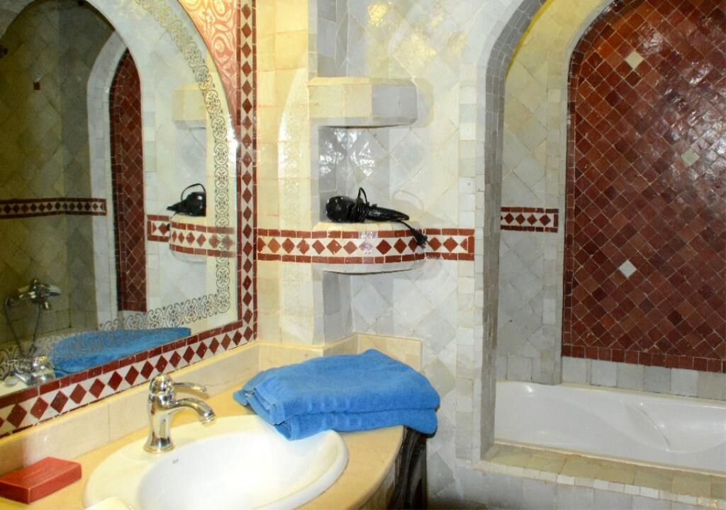 A bathroom with a sink, mirror, and bathtub.