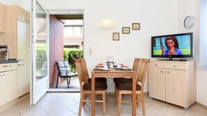 Een moderne keuken met een eethoek, een televisie en uitzicht op buiten.