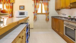 Une cuisine avec des meubles en bois, un four à micro-ondes, une cuisinière et des rideaux colorés.