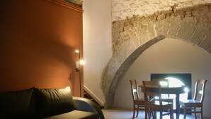 A cozy room with a sofa, a table with chairs, and a stone archway. - Châtelet de Barbençon (Beaumont)