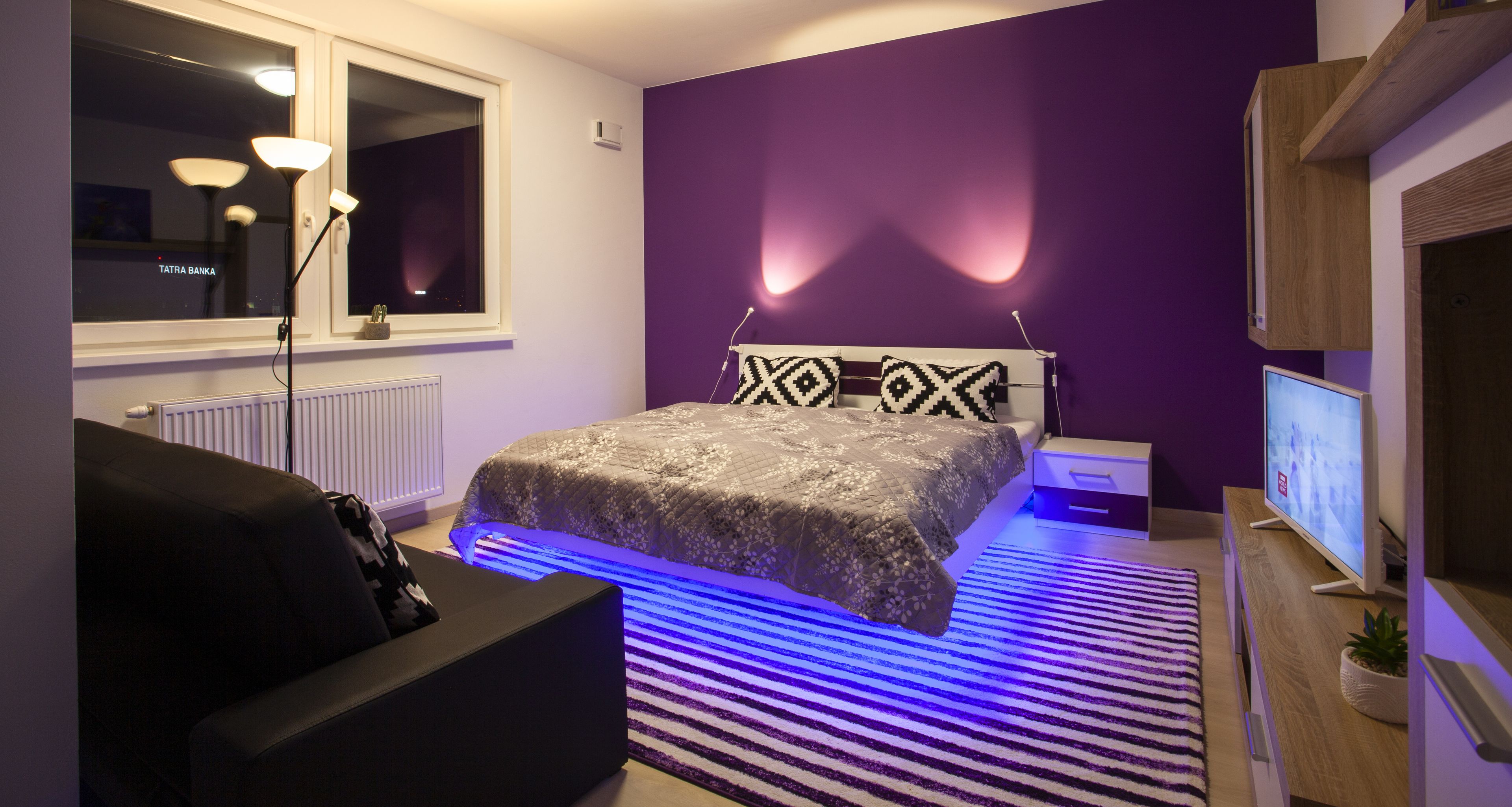 Een moderne slaapkamer met een bed, nachtkastje en televisie.