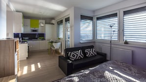Eine moderne Wohnung mit Küche, Essbereich und Wohnzimmer, ausgestattet mit einer Couch und einem Bett.