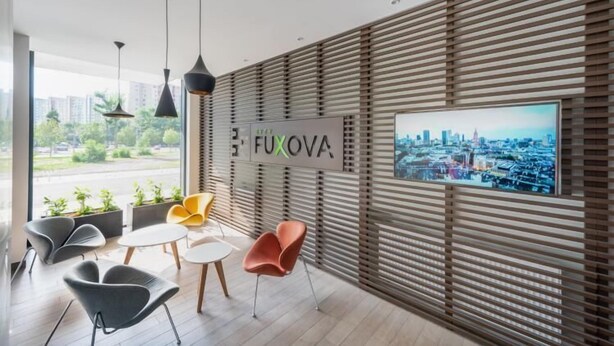 Ein modernes Interieur mit Blick auf die Stadt, ein Schild mit der Aufschrift "FUXOVA" und moderne Möbel.