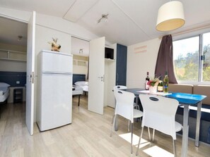 A compact room with a kitchenette, a dining area with a table and chairs, and a window with a view. - Vacation home Palma by Interhome (Novigrad (Zadar))