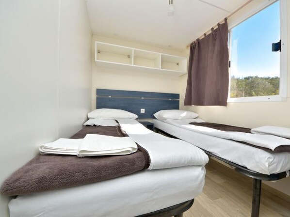 Une chambre d’hôtel avec deux lits, une fenêtre avec des rideaux et une vue sur l’extérieur.