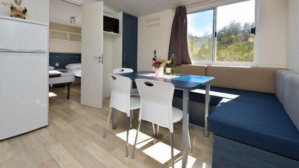 A compact room with a kitchenette, a dining area with a table and chairs, a sofa, and a large window offering a view of greenery. - Vacation home Palma by Interhome (Novigrad (Zadar))