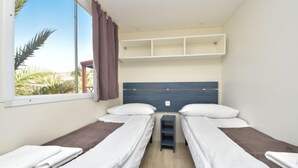 A room with two single beds, a window with curtains, a headboard, and a small shelf unit. - Vacation home Palma by Interhome (Novigrad (Zadar))