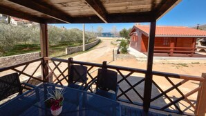 A covered outdoor seating area with a table and chairs, overlooking a rural road and a red-roofed building. - Vacation home Palma by Interhome (Novigrad (Zadar))