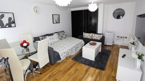 Une chambre moderne et bien éclairée, comprenant un lit, deux canapés, un bureau et un téléviseur.