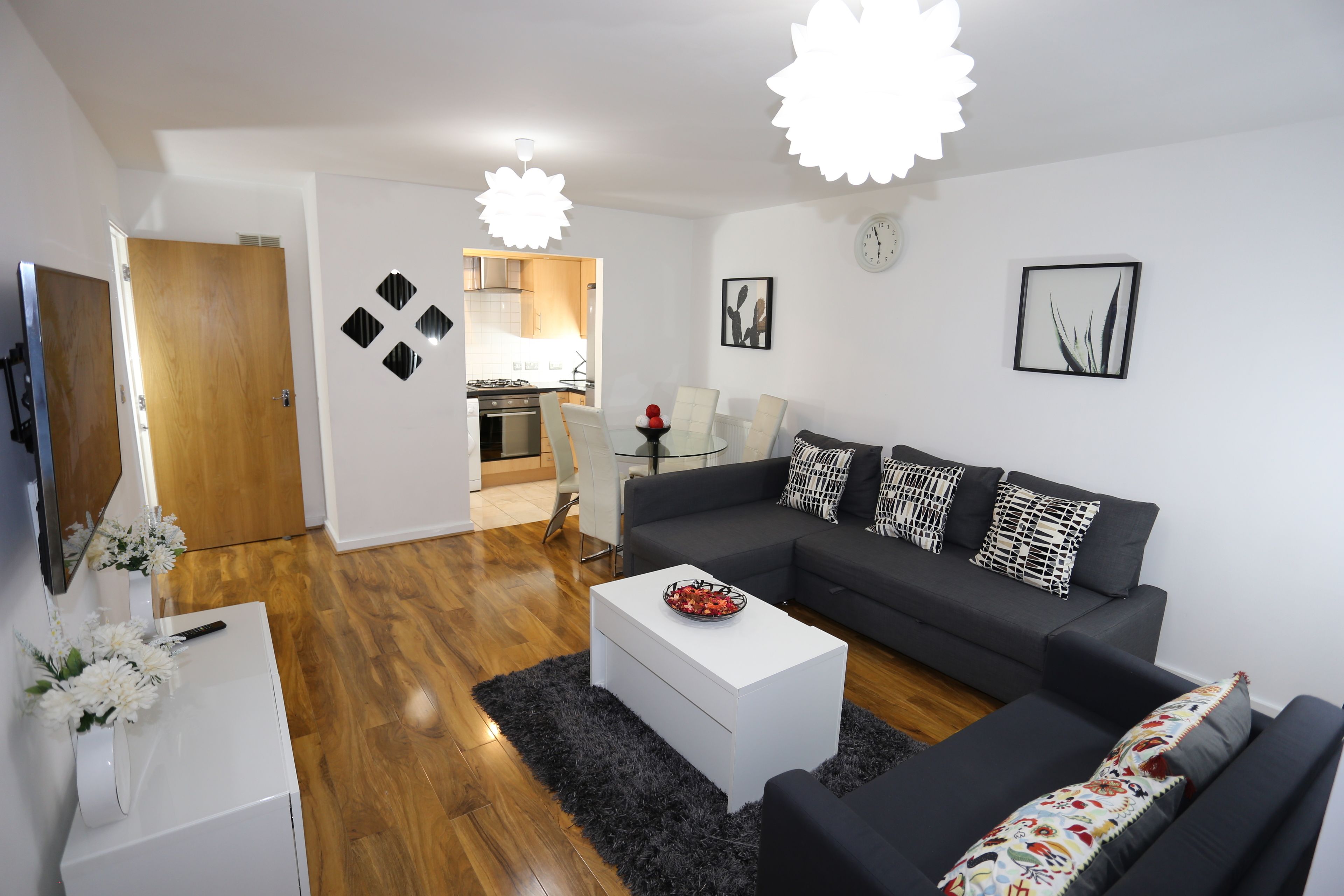 A modern living room with a sofa, coffee table, and a dining area with chairs.