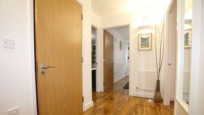 A hallway with wooden flooring, white walls, and a wooden door. - 2 Beds Riverview Tideslea Apartment (London)