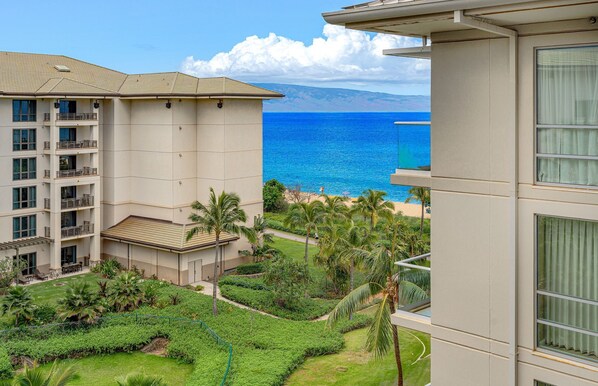 A multi-story hotel with balconies overlooking a beach and ocean.