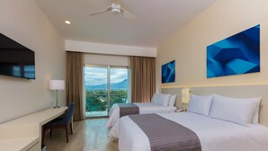 A hotel room with two beds, a desk, a chair, a TV, and a large window with a view of the city. - Krystal Vallarta - All Inclusive (Puerto Vallarta)