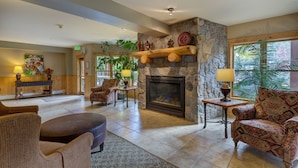 A spacious lobby with a stone fireplace, comfortable seating, and a large window offering a view of greenery. - Walk to Mountain House, Great Slope Views, Private Laundry, Shared Hot Tubs (Keystone)