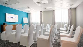 A conference room with white chairs, a TV screen, and a blue wall.