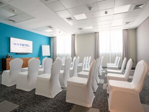 Ein Konferenzraum mit weißen Stühlen, einem Fernsehbildschirm und einer blauen Wand.