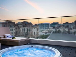 A rooftop terrace with a hot tub, seating area, and a city view at sunset. - Novotel Bur Dubai (Dubai)