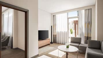 Een moderne hotelkamer met een flatscreen televisie, een ronde salontafel, een bank en een stoel.